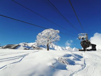 Ski lift over snow covered mountains against clear blue sky