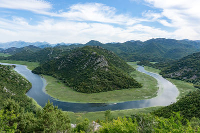 Scenic view of river against green mountains