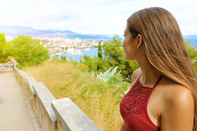 Beautiful woman standing in park against sky