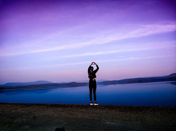 Full length of woman standing on shore against sky during sunset