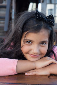 Close-up portrait of smiling girl sitting on table