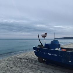Boat moored on beach against sky