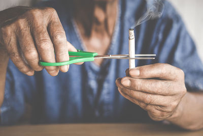 Midsection of man cutting cigarette