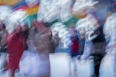 Blurred motion of people walking in multi colored umbrella