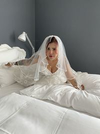 Portrait of bride sitting on bed at home