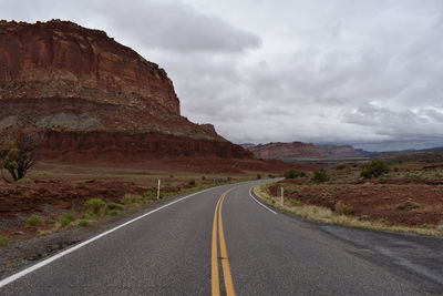 Road leading towards mountains against sky