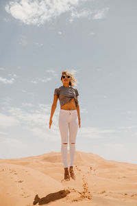 Full length of woman standing on beach against sky