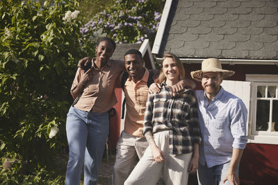 Smiling friends standing in front of wooden house