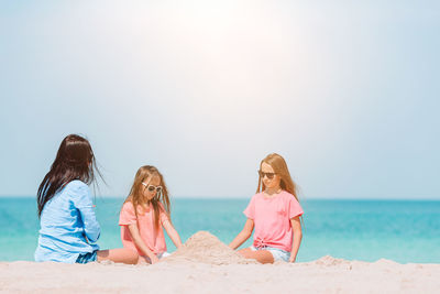 People sitting on beach against sky