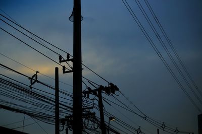 Low angle view of electricity pylon against sky at sunset