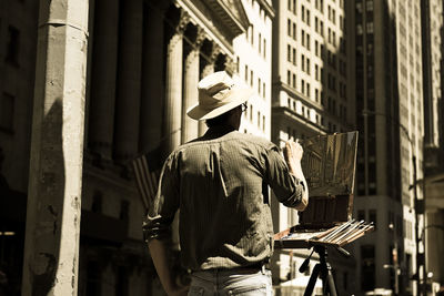 Rear view of man standing against buildings in city