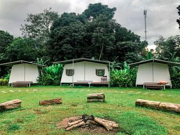 House and trees on field against sky