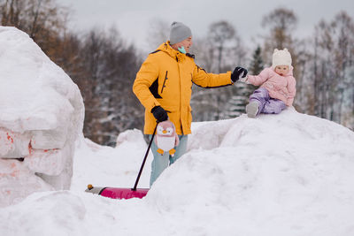 Little girl in pink walks with her dad outdoors on winter snowy day