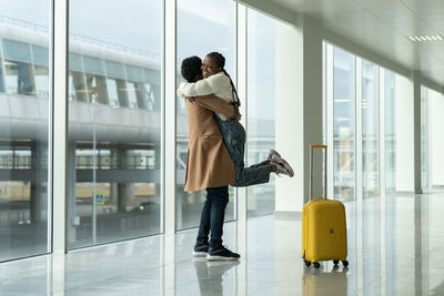 Happy meeting at airport. african man met and embrace woman after arrival in empty modern terminal