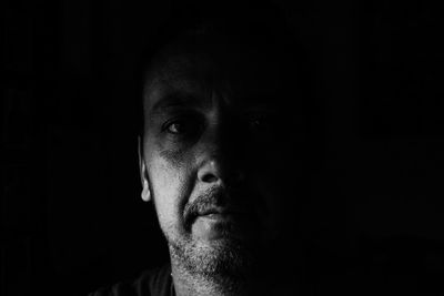 Close-up portrait of man against black background