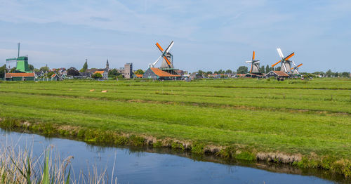 Built structure on field by river against sky