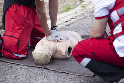 Midsection of paramedics performing cpr on mannequin