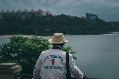 Rear view of photographer standing against sea