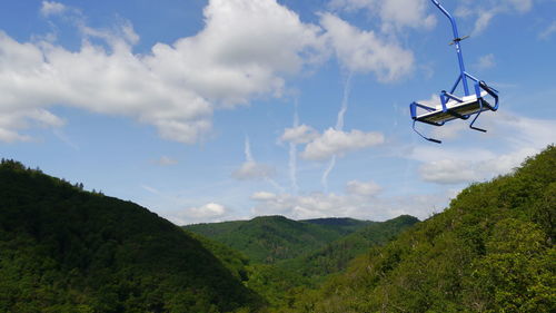 Low angle view of chairlift flying against sky