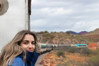 Woman posing on a running train with desert landscape in the background. arizona, usa