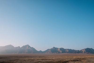 Scenic view of desert against clear blue sky