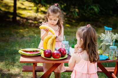 Sisters having fruits in yard