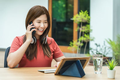 Young woman using phone on table