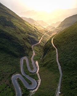 Scenic view of road among mountains against sunny sky