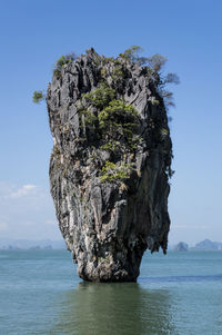 Rock formation in sea against blue sky