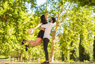 Man carrying girlfriend against trees at forest