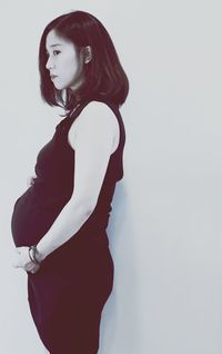 Pregnant woman standing by white background