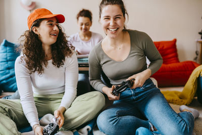 Happy female friends playing video game at home