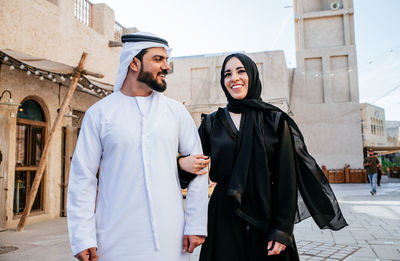 Smiling couple wearing traditional clothing talking while walking on street in town