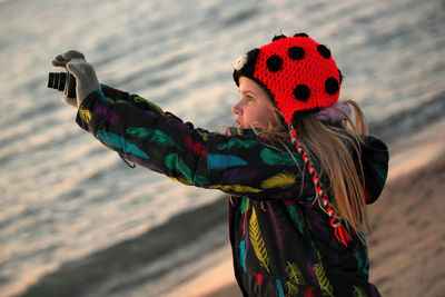 A 9 year old girl practices her photography and camera skills at the beach in the evening