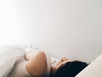 Rear view of woman lying on bed at home