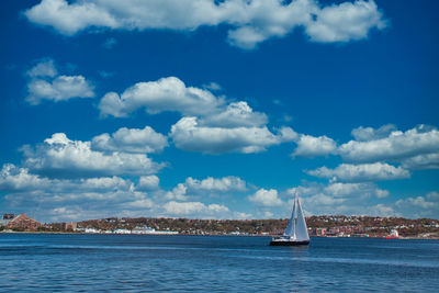 Sailboat on sea by buildings against sky