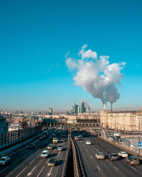 Cars on road in city against blue sky