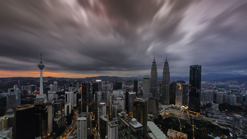 High angle view of cityscape against cloudy sky at night