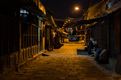 Footpath amidst illuminated buildings in city at night