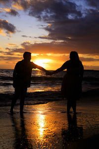 A young couple walking on the beach at sunset