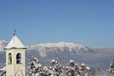 Trentino alto adige, rovereto in winter. church and snowcapped mountains against clear sky