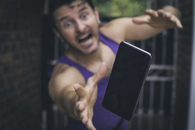 Man reaching towards falling mobile phone outdoors