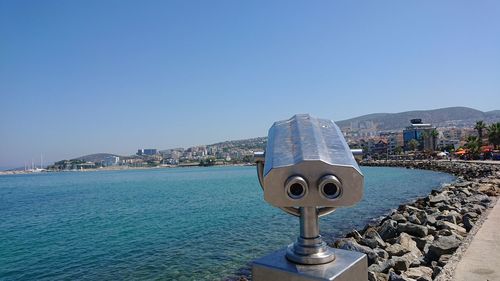 View of sea and buildings against clear blue sky