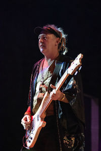 Man playing guitar against black background