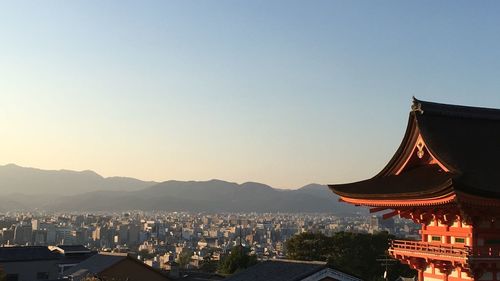 Temple and buildings in city against clear sky