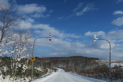 Road amidst trees against sky during winter