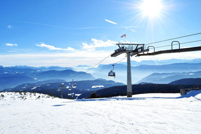 Ski lift over snowcapped mountains against sky