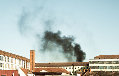 Smoke emitting from chimney against sky