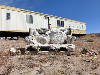 Abandoned sofa on field against travel trailer