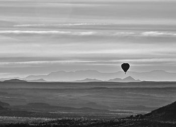 Hot air balloon flying over sea against sky